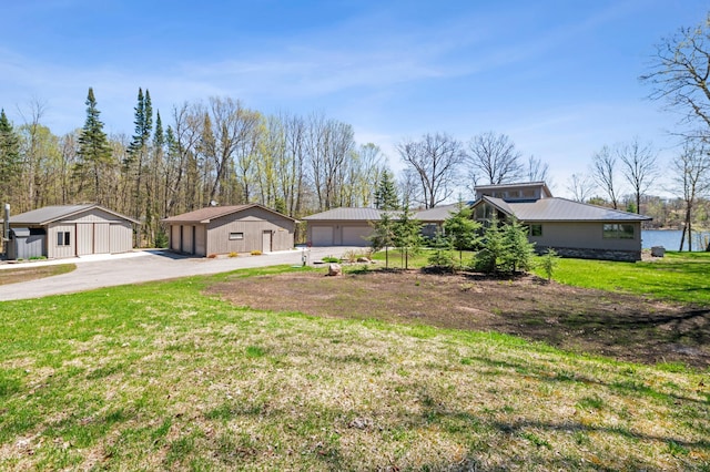mid-century home featuring a detached garage, metal roof, an outdoor structure, and a front yard