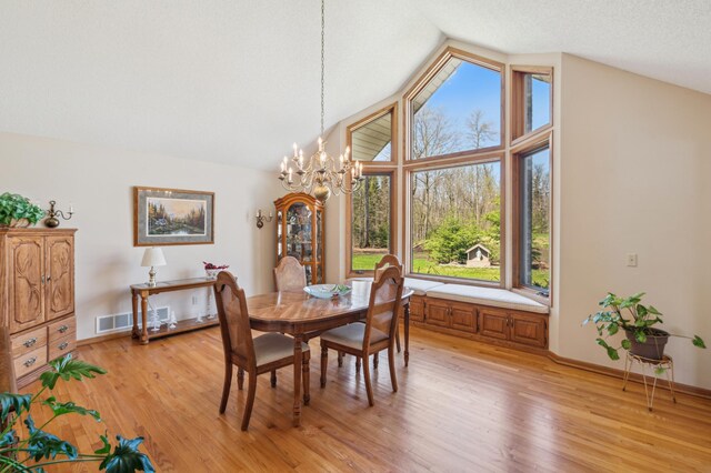 dining area featuring a chandelier, vaulted ceiling, light wood-style floors, and baseboards