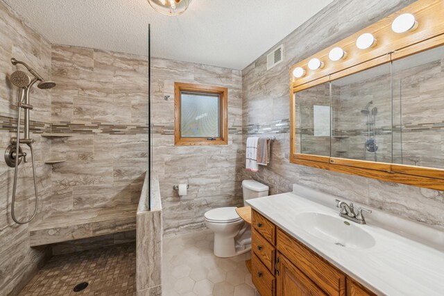full bathroom featuring tile walls, walk in shower, vanity, toilet, and tile patterned flooring