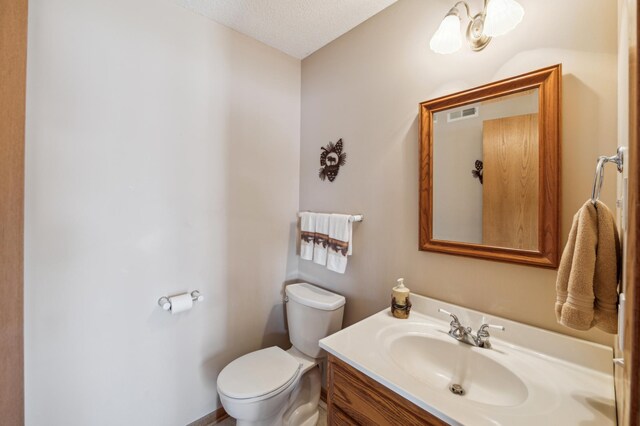 bathroom with toilet, vanity, and a textured ceiling