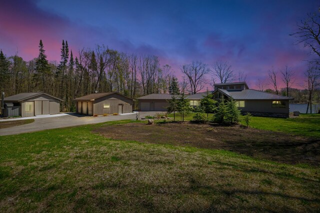 mid-century inspired home featuring a detached garage, an outdoor structure, a lawn, and metal roof