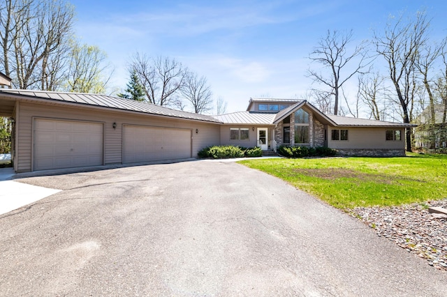 30501 336th Ln, Aitkin, MN 56431 - view of front of property featuring driveway, a garage, a front lawn, stone siding, and metal roof