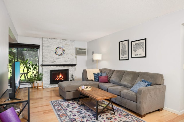 4508 Cedar Lake Rd S Unit 2, Saint Louis Park, MN 55416 - living area featuring a baseboard radiator, a wall unit AC, a brick fireplace, and light wood-style flooring