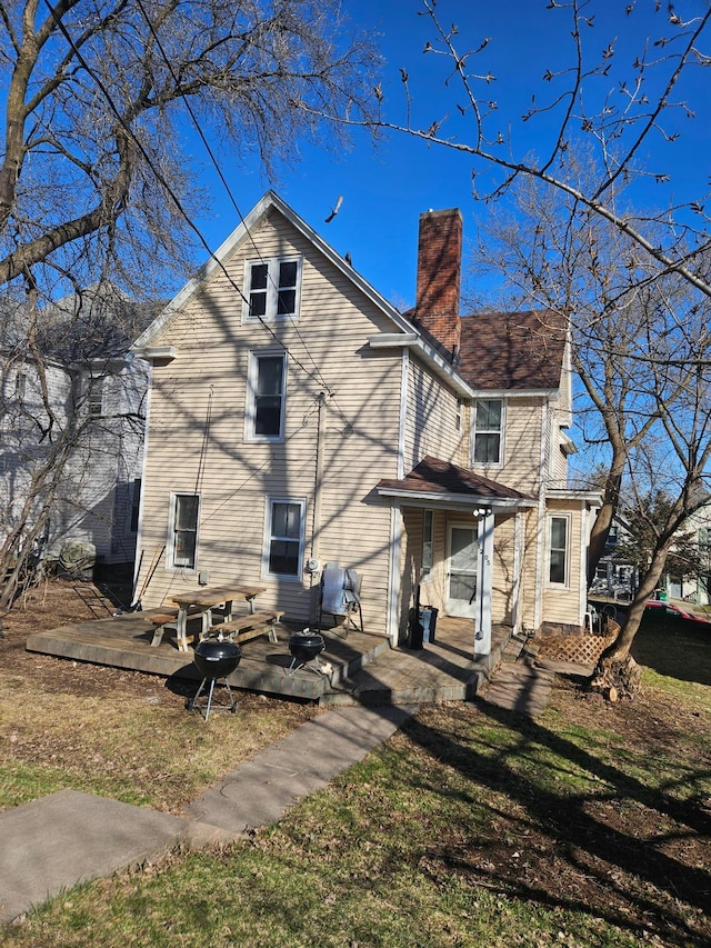 rear view of property with a chimney and a yard