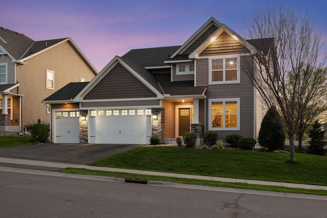 craftsman-style home with driveway, an attached garage, a front yard, central AC unit, and stone siding
