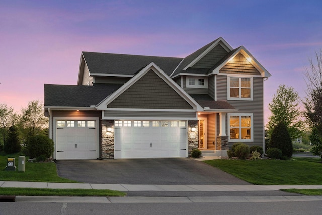 craftsman-style home with driveway, a lawn, a garage, and stone siding