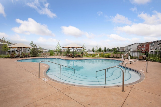 community pool with fence, a patio area, and a residential view
