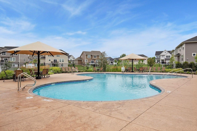 community pool featuring a residential view, fence, and a patio area