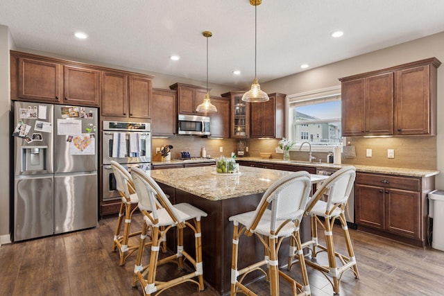 6573 Bridle Path, Corcoran, MN 55340 - kitchen featuring stainless steel appliances, a kitchen island, light stone countertops, a kitchen bar, and decorative backsplash