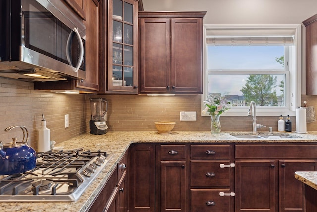 6573 Bridle Path, Corcoran, MN 55340 - kitchen with appliances with stainless steel finishes, a sink, tasteful backsplash, glass insert cabinets, and light stone countertops