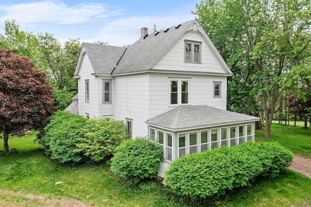 52905 Deerwood Ave, Rush City, MN 55069 - view of side of property featuring roof with shingles, a chimney, a lawn, and a sunroom