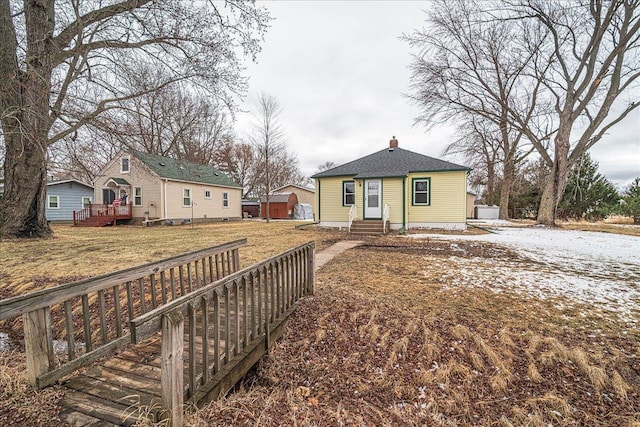 bungalow-style home with a deck, a front yard, a chimney, and entry steps
