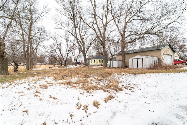 yard layered in snow featuring an outdoor structure and a storage unit