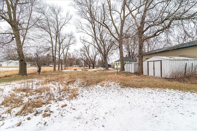 snowy yard with a storage shed and an outbuilding