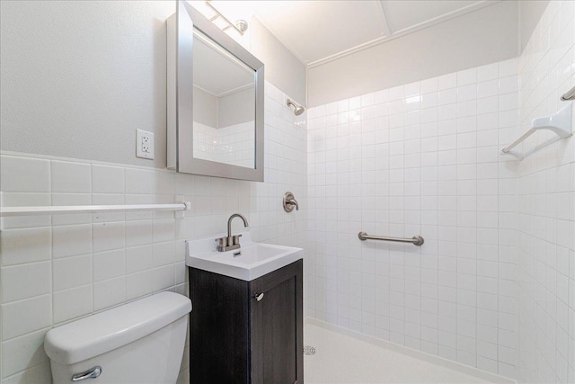 bathroom featuring vanity, a tile shower, and toilet