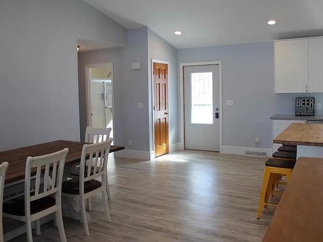 dining space with light wood-style floors, baseboards, vaulted ceiling, and recessed lighting