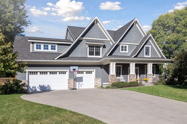 craftsman-style house featuring a garage, covered porch, stone siding, a front yard, and driveway
