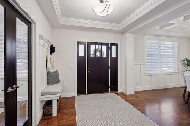 entrance foyer with crown molding, a tray ceiling, wainscoting, and wood finished floors
