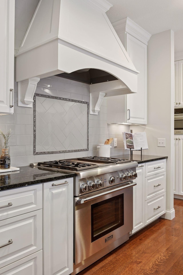 kitchen with decorative backsplash, stainless steel range, custom exhaust hood, and white cabinets