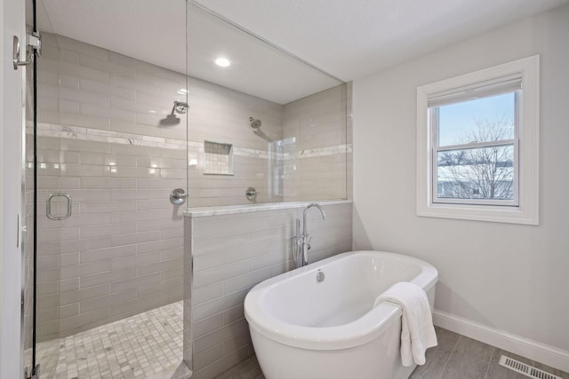 bathroom featuring a freestanding bath, recessed lighting, baseboards, a shower stall, and visible vents