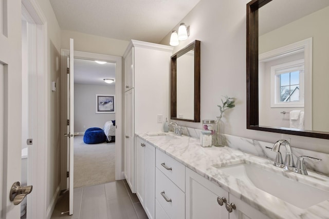 bathroom featuring a sink, tile patterned floors, ensuite bathroom, and double vanity