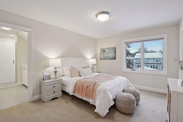 bedroom featuring light colored carpet, baseboards, and ensuite bath