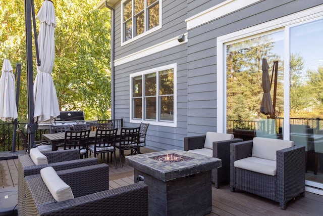 deck featuring grilling area, outdoor dining area, and a fire pit
