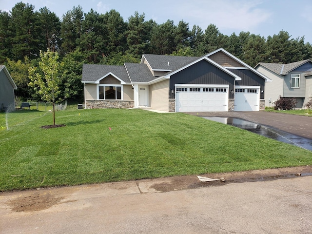 10815 190th Ln NW, Elk River, MN 55330 - view of front facade with driveway, roof with shingles, a front lawn, an attached garage, and stone siding