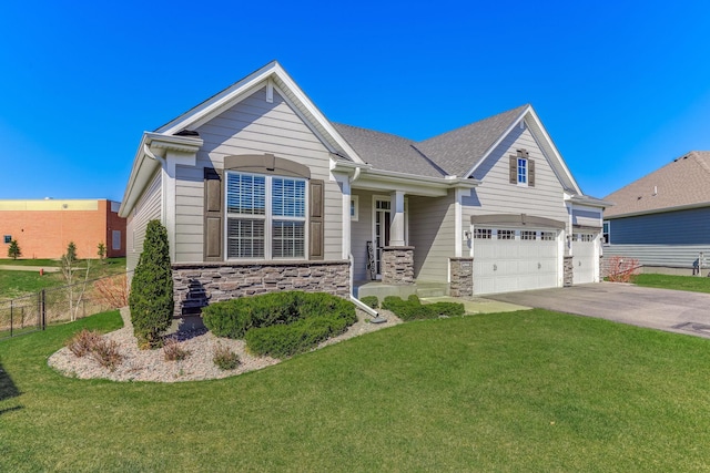 craftsman house featuring fence, driveway, a front lawn, and stone siding