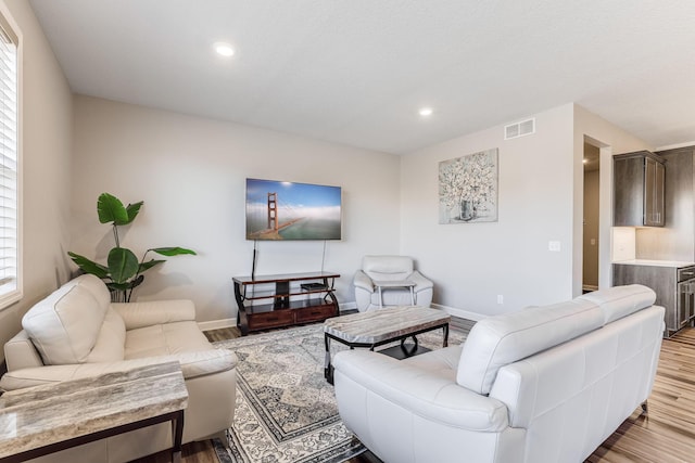 living room with recessed lighting, visible vents, and wood finished floors