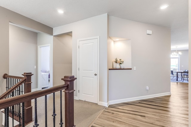 hallway with an inviting chandelier, baseboards, an upstairs landing, light wood-style floors, and recessed lighting