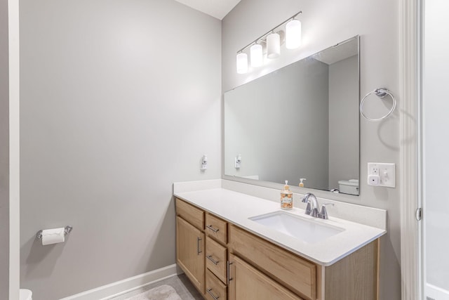 bathroom with vanity, baseboards, and toilet