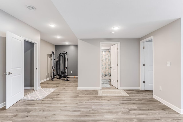 exercise area featuring baseboards, recessed lighting, and light wood finished floors