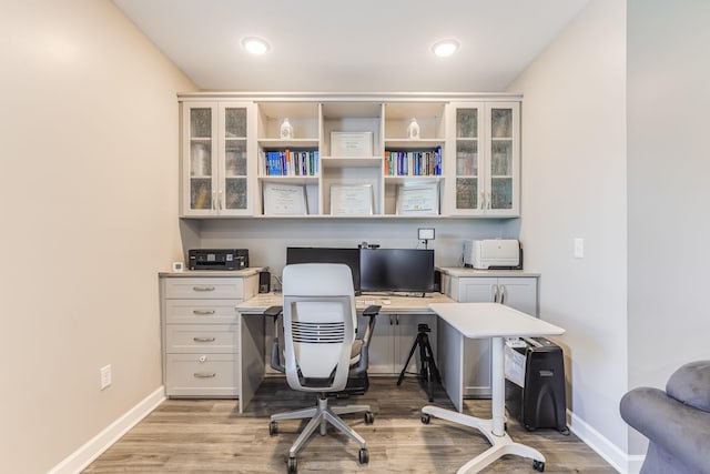 office space with baseboards, light wood-style flooring, and built in study area