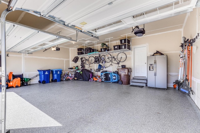 garage featuring stainless steel fridge and a garage door opener