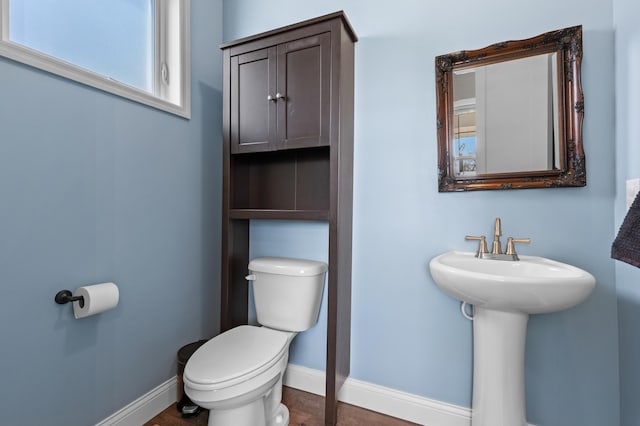 bathroom with baseboards, toilet, and wood finished floors