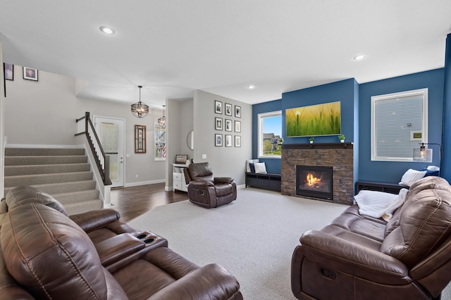 living room with stairs, recessed lighting, a stone fireplace, baseboards, and wood finished floors