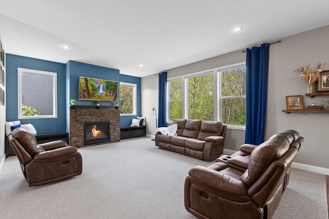carpeted living area featuring baseboards, a stone fireplace, and recessed lighting