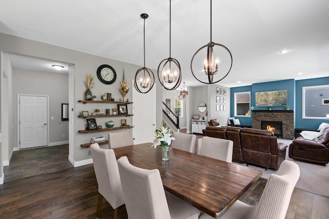 dining area with a chandelier, dark wood-style flooring, stairway, baseboards, and a fireplace