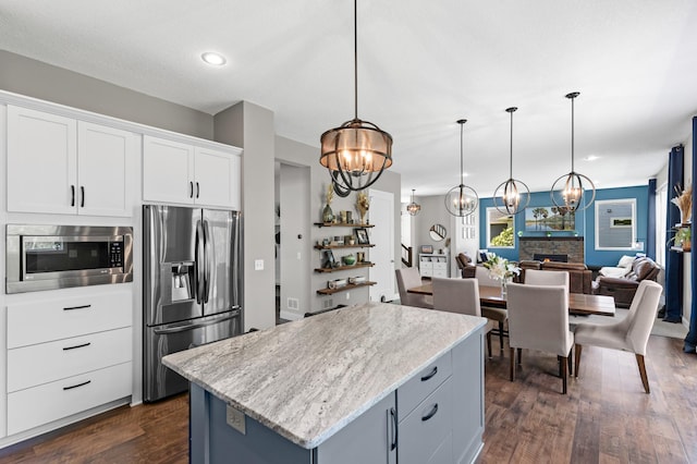 kitchen with appliances with stainless steel finishes, a chandelier, a center island, dark wood-style flooring, and white cabinets