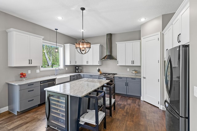kitchen with appliances with stainless steel finishes, wall chimney range hood, a sink, wine cooler, and a kitchen breakfast bar