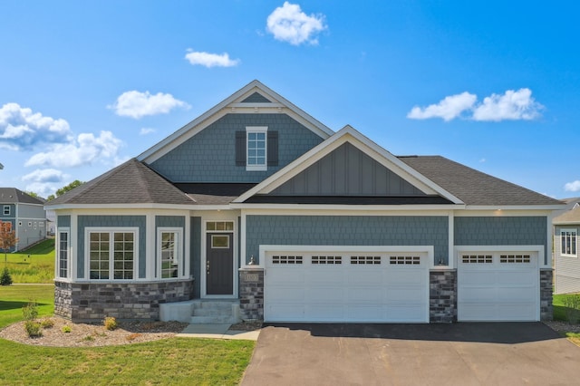 craftsman house with stone siding, a garage, asphalt driveway, and board and batten siding