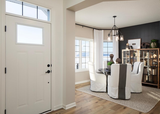 foyer featuring baseboards, wood finished floors, and a chandelier