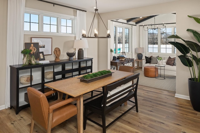 dining space featuring a chandelier, wood finished floors, and baseboards