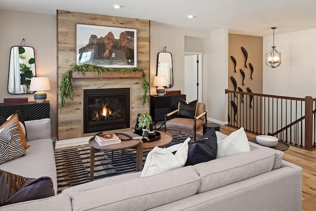 living area featuring wood finished floors, a premium fireplace, a chandelier, recessed lighting, and baseboards