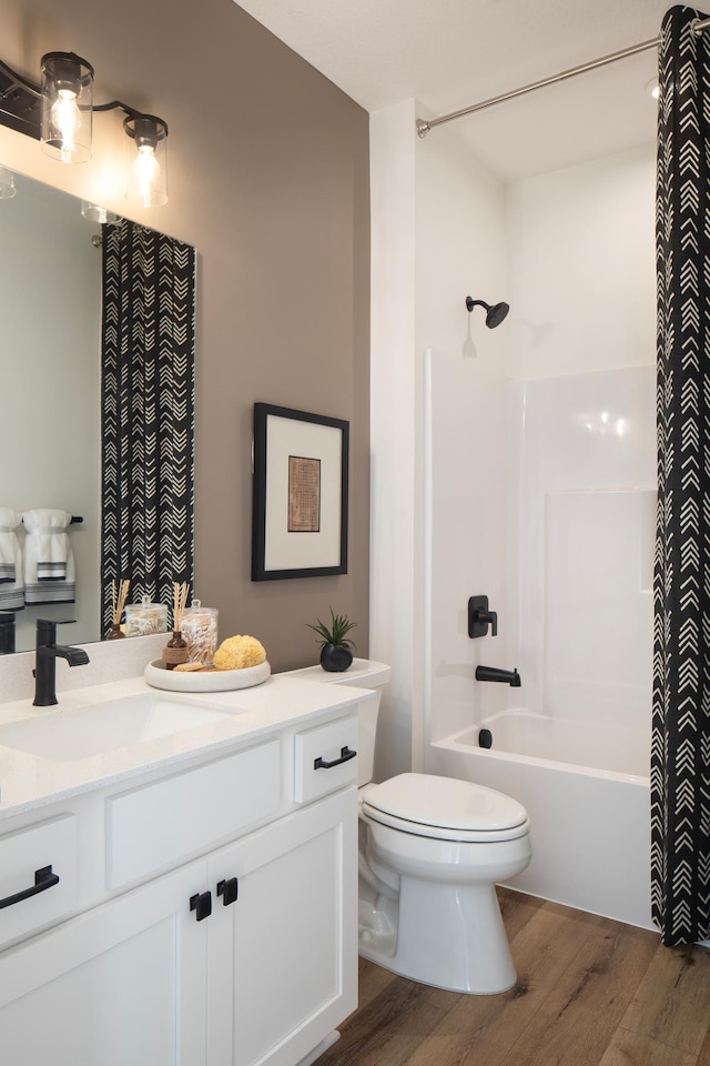 bathroom featuring wood finished floors, toilet, vanity, and shower / bath combo