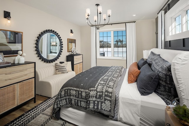 bedroom with wood finished floors, a chandelier, and a water view