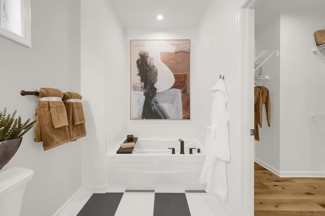 bathroom featuring a garden tub, recessed lighting, wood finished floors, baseboards, and toilet