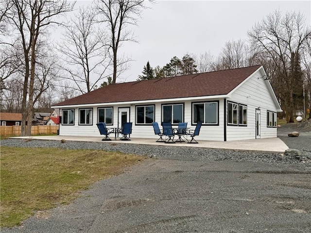 back of house featuring fence, a patio, and a shingled roof