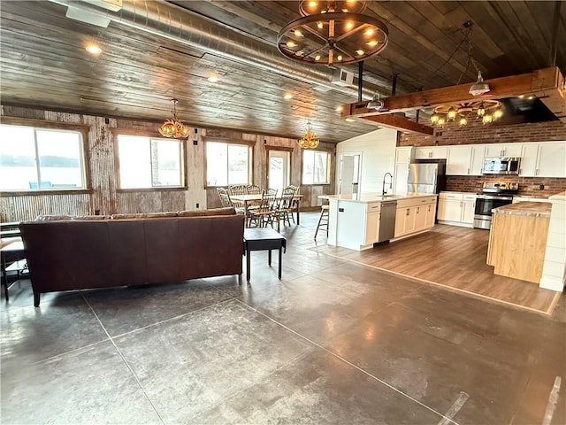 living area with wood ceiling, plenty of natural light, concrete flooring, and a chandelier